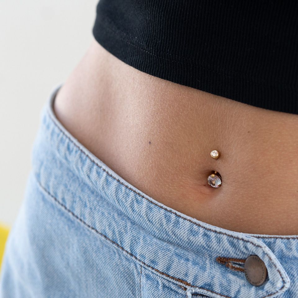 Vergulde navelpiercing met een grote steen